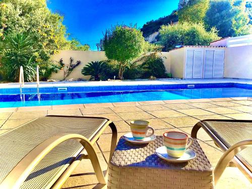 a table with two cups on it next to a pool at Villa Rossa in Pissouri