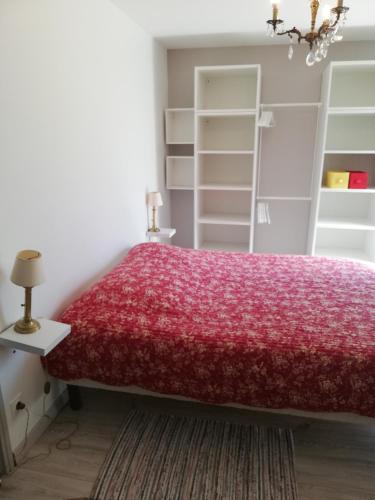 um quarto com uma cama vermelha e prateleiras brancas em Appartement de plain pied dans la verdure em Yerres