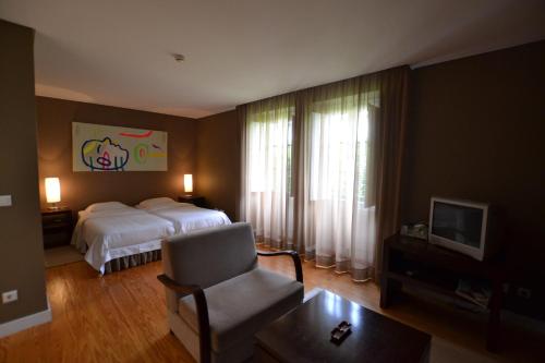 a hotel room with a bed and a chair at Casa do Campo - Turismo de Habitação in Celorico de Basto