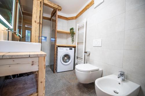 a bathroom with a toilet sink and a washing machine at Apartments Berna in Ortisei