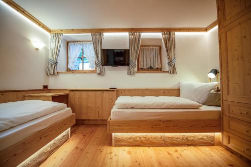 two beds in a room with wooden floors and windows at Apartments Berna in Ortisei