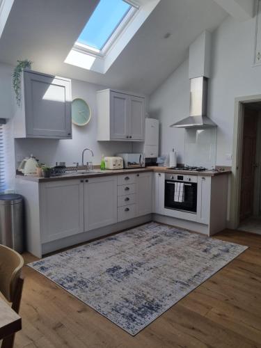 a kitchen with white cabinets and a rug on the floor at 19a Brooks Road in Street