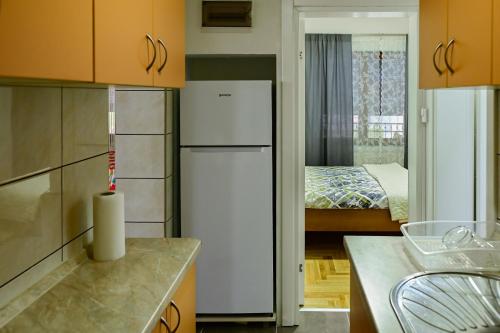 a kitchen with a white refrigerator and a bedroom at Town side Čelinac in Čelinac