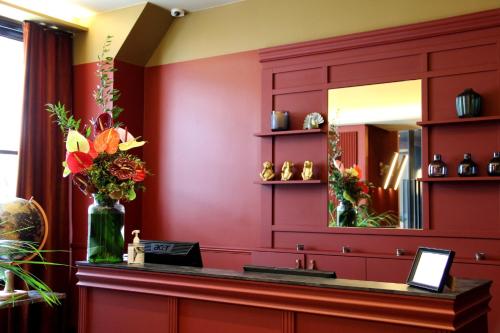a bathroom with red walls and a sink with a mirror at Hotel Le Rocroy in Paris