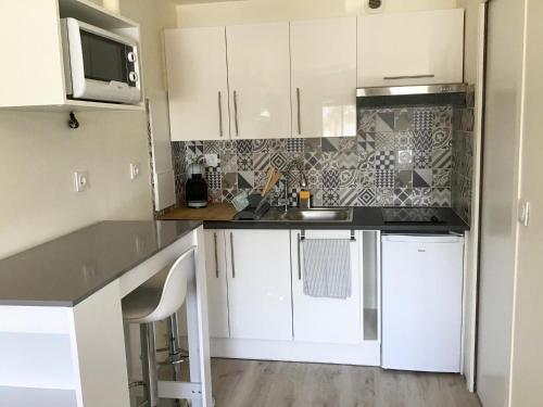 une cuisine avec des armoires blanches, un évier et un micro-ondes dans l'établissement Studio La Rochelle-Ré, à La Rochelle