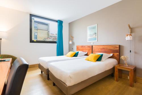 two beds in a hotel room with blue curtains at Victoria Garden Bordeaux Centre in Bordeaux