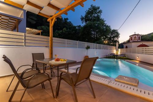 a patio with a table and chairs next to a swimming pool at AGNONTAS LUXURY VILLAS in Agnontas