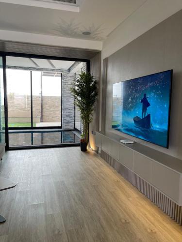 AB Villa في عجمان: غرفة معيشة مع تلفزيون بشاشة مسطحة كبيرة على جدار