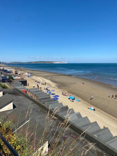 a beach with people on the sand and the ocean at The Bay house Apartments , shanklin in Shanklin