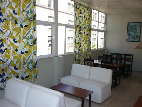 una sala de espera con sillas blancas, mesa y ventanas en Hotel Ancon, en Buenos Aires