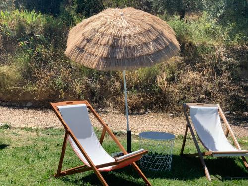two chairs and an umbrella in the grass at Apartamentos la Jayma del Arte in Asque