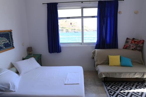 a bedroom with a bed and a couch and a window at Sunrise seahouse in Vromopoúsi