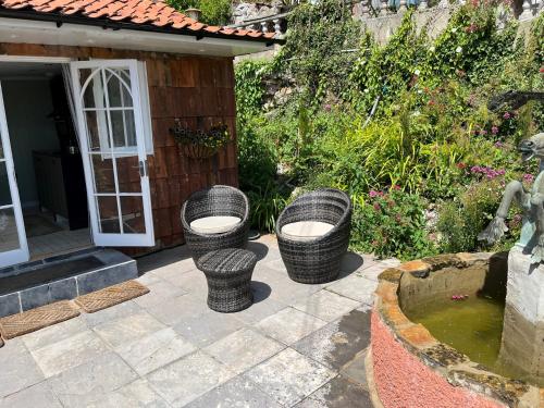 three wicker chairs sitting on a patio near a fountain at The Little Fountain House in Dawlish