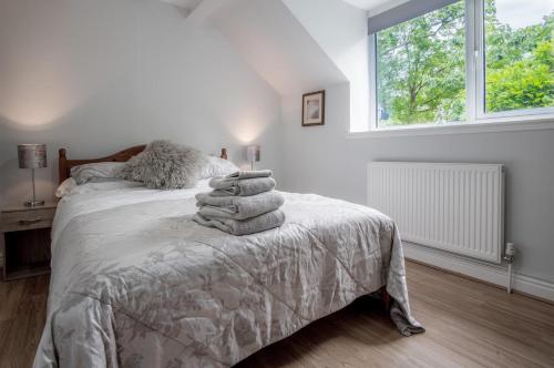 Un dormitorio blanco con una cama con toallas. en Wern Y Glais - 2 Bedroom Cottage - Glais en Swansea