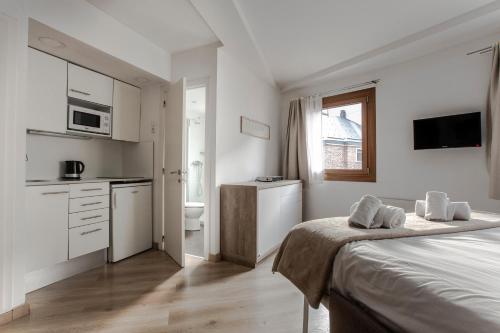 a white room with a bed and a kitchen at Outdoor Apartaments - Basecamp in Andorra la Vella