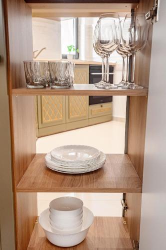 a kitchen with wine glasses and plates on a shelf at Riviera Residence Apartments in Mamaia