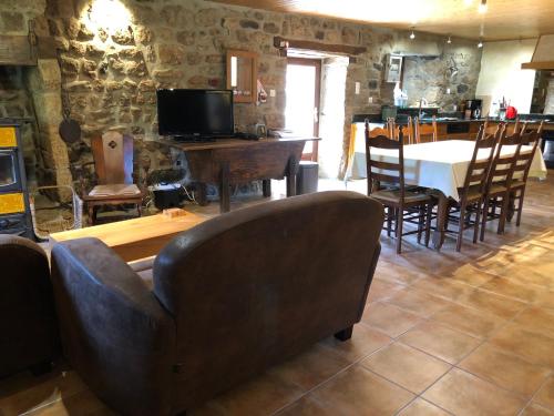un salon avec une table, des chaises et un canapé dans l'établissement Maison Coquelicot, à Chanéac