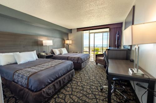 a hotel room with two beds and a desk at Seaview Hotel in Virginia Beach
