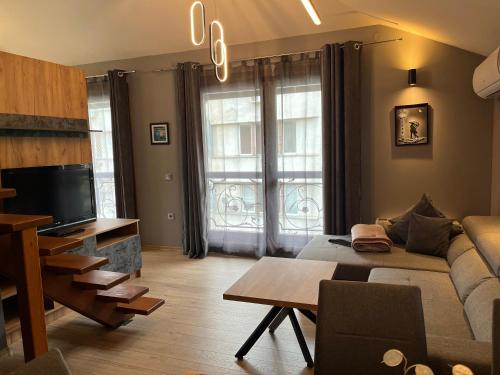a living room with a couch and a tv at Апартаменти за гости ,,Friends" in Teteven