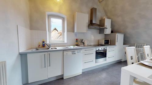 une cuisine avec des armoires blanches et une fenêtre dans l'établissement Tel un songe blanc, à Colmar