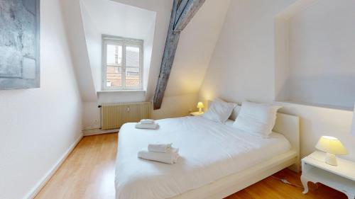 une chambre avec un lit blanc avec deux serviettes dessus dans l'établissement Tel un songe blanc, à Colmar
