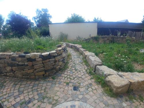 una pared de retención de piedra junto a un patio en Monteur- und Ferienwohnung Gemmer 52qm, en Herold