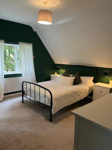 a bedroom with a bed with green walls at Ruby Cottage in Clabby