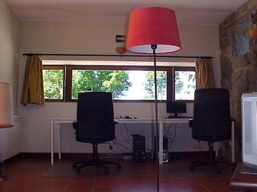 an office with a desk with two chairs and a red lamp at Stone Farm Hostel in Felgueiras