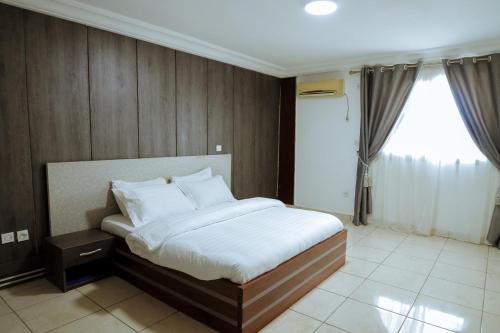 a bedroom with a bed with white sheets and a window at RESIDENCE OLIE OFFICIEL in Douala