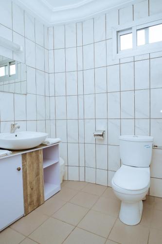 a white bathroom with a toilet and a sink at RESIDENCE OLIE OFFICIEL in Douala