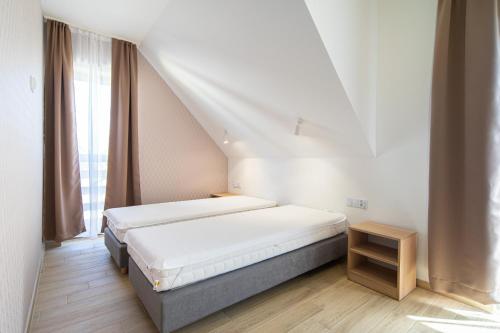 a white bedroom with a bed and a window at Villa Arkadia PORTUS in Dziwnów