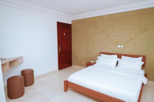 a bedroom with a bed with white sheets and pillows at RESIDENCE OLIE OFFICIEL in Douala