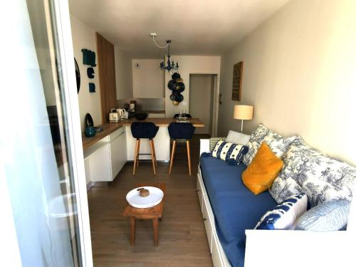 un salon avec un canapé bleu et une cuisine dans l'établissement Le Palais Blanc - A 90m de la Grande Plage - Parking prive, à Les Sables-dʼOlonne
