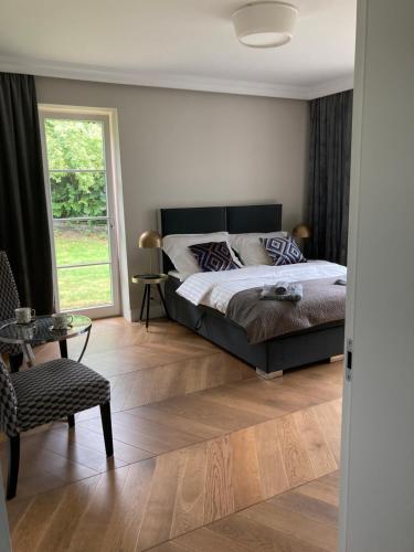 um quarto com uma cama, uma janela e uma cadeira em Kraków Green Hill Luxury Apartment em Balice