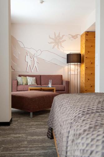 a living room with a couch and a bed at Sporthotel Pontresina in Pontresina