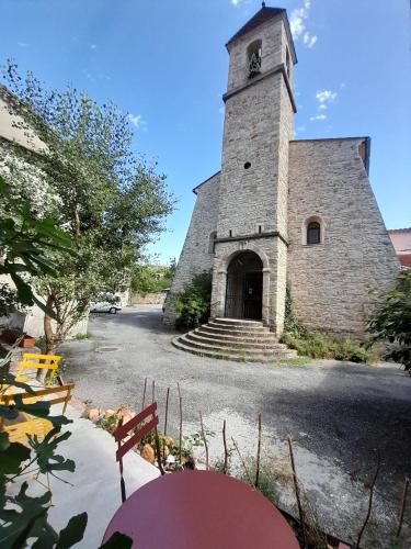 un grand bâtiment en pierre avec une tour d'horloge dans l'établissement LE PRIEURE, à Saint-Florent-sur-Auzonnet