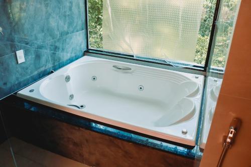 a bath tub in a bathroom with a window at Pousada Mirante do Penedo in Penedo