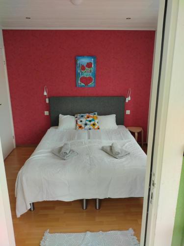 a bedroom with a white bed with a red wall at Kvarngården Natur Resort in Byxelkrok