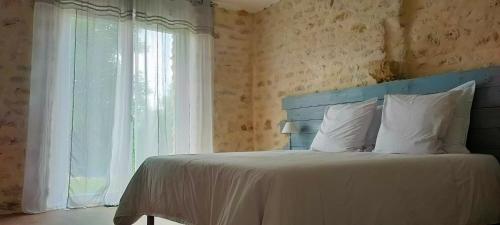 a bedroom with a bed with a blue headboard and a window at Le Petit Pré in Bouesse