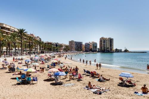 eine Gruppe von Menschen mit Sonnenschirmen an einem Strand in der Unterkunft Playa del Cura apartment with 2 bedrooms in Torrevieja