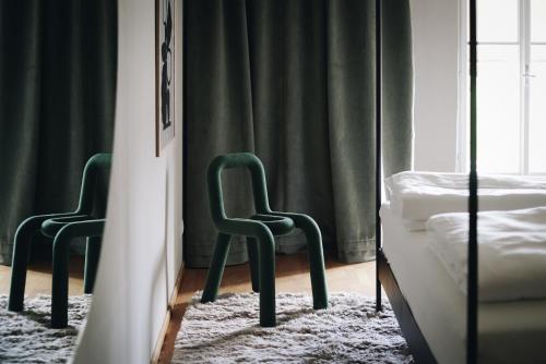 two green chairs in a bedroom with a bed at MÜHLENHOF ROOMS boutique bed & breakfast in Langenlois