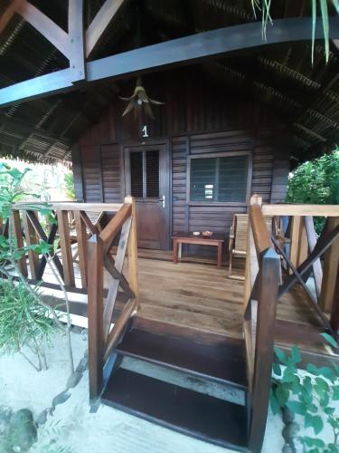 a front porch of a thatched house with a wooden deck at Le Moya Beach in Nosy Be