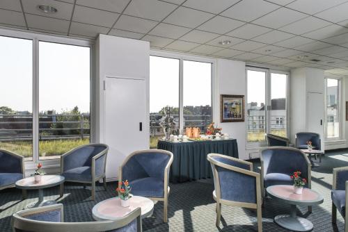 a waiting room with tables and chairs and windows at ibis Berlin City Nord in Berlin