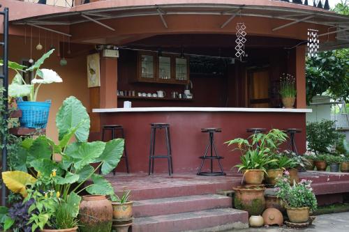 a red house with a bar and some plants at SukSanti CoLiving and Vacation in Chiang Rai