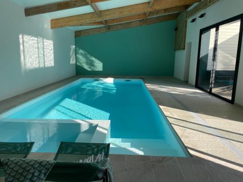 - une piscine avec 2 chaises dans une maison dans l'établissement Villa La Luciole Piscine interieure, à Barneville-Carteret