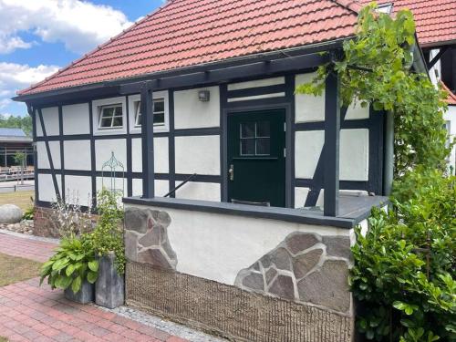 una casa blanca y negra con una puerta verde en Ferienwohnung im Landhaus Labes (Stechlinsee) en Neuglobsow