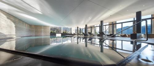 a swimming pool in a building with windows at Das Tegernsee in Tegernsee