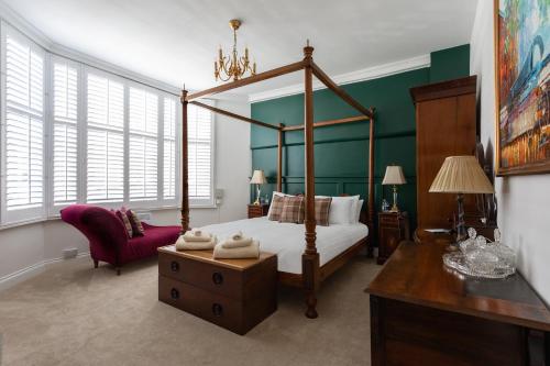a bedroom with a canopy bed and a chair at Staycations Maldon in Maldon