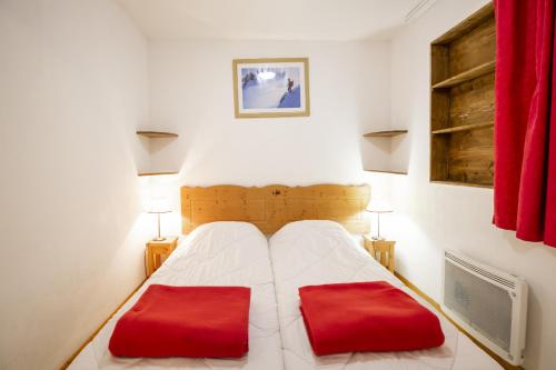 um quarto com uma cama com duas almofadas vermelhas em Les Balcons PROCHE PARC NATIONAL VANOISE studios em Termignon
