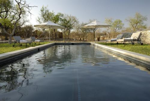 una piscina de agua con sillas y sombrillas en The Mushara Outpost, en Namutoni